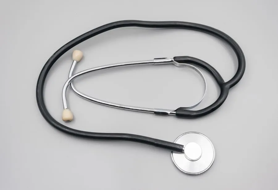 A black stethoscope coiled on a plain grey surface