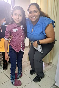 A child standing beside a member of the team who is holding a clipboard