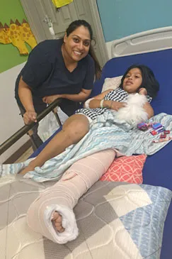 A girl resting in a hospital bed with a bandaged leg