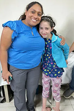 A girl in pyjamas standing beside a member of the team