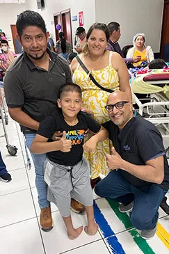 A boy giving a thumbs up beside a member of the team