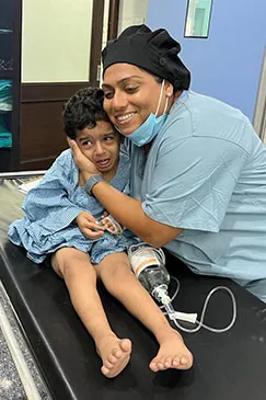 A member of the team hugging a child whose leg is in a cast